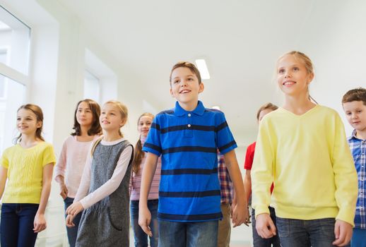 education, elementary school, drinks, children and people concept - group of smiling school kids walking in corridor