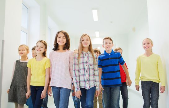 education, elementary school, drinks, children and people concept - group of smiling school kids walking in corridor