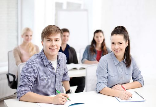 school and education concept - group of smiling students with notebooks at school