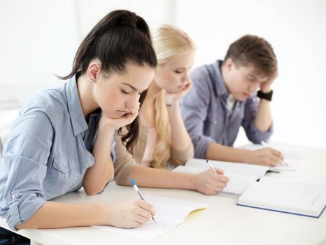 school and education concept - group of tired students with notebooks at school