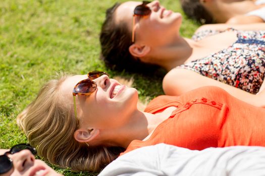 friendship, leisure, summer and people concept - group of smiling friends lying on grass outdoors