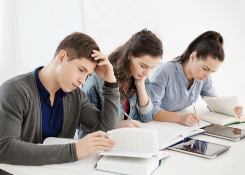 school and education concept - group of tired students with notebooks at school