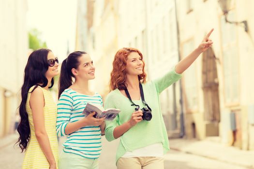 tourism, travel, leisure, holidays and friendship concept - smiling teenage girls with city guide and camera outdoors