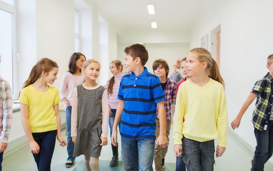 education, elementary school, drinks, children and people concept - group of smiling school kids walking in corridor