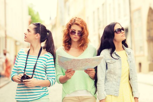 tourism, travel, leisure, holidays and friendship concept - teenage girls with map and camera outdoors