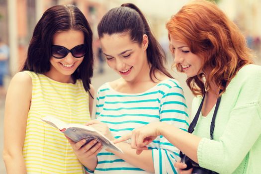 tourism, travel, leisure, holidays and friendship concept - smiling teenage girls with city guide and camera outdoors