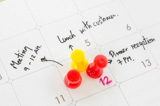 Pushpin on calendar with busy day overworked schedule.