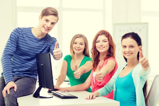 education, technology, school and people concept - group of smiling students showing thumbs up in computer class at school