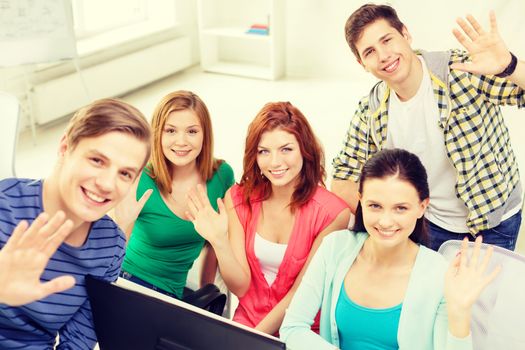 education, technology, school and people concept - group of smiling students waving hands in computer class at school