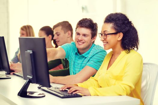 education, technology and school concept - smiling students in computer class at school