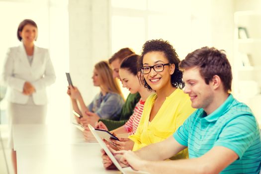 education, technology and internet concept - smiling female students with tablet pc computer and friends on the back at school