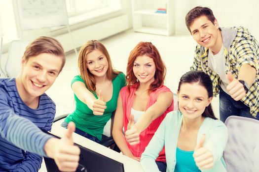 education, technology, school and people concept - group of smiling students showing thumbs up in computer class at school