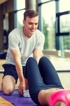 sport, fitness, lifestyle and people concept - smiling woman with male personal trainer exercising in gym