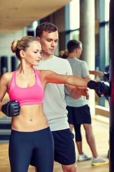 sport, fitness, lifestyle and people concept - smiling woman with personal trainer boxing in gym