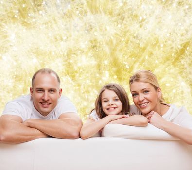 family, childhood, holidays and people - smiling mother, father and little girl over yellow lights background