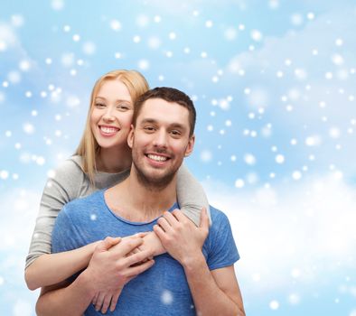 love, people and family concept - smiling couple hugging over blue sky, snow and cloud background