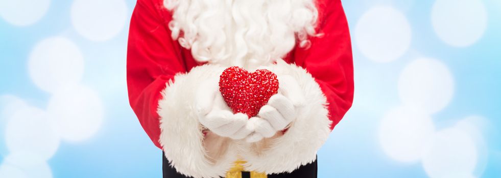 christmas, holidays, love, charity and people concept - close up of santa claus with heart shape decoration over blue lights background