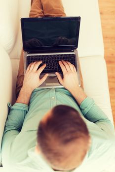 technology, leisure, advertisement and lifestyle concept - close up of man working with laptop computer and sitting on sofa at home