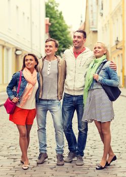 friendship, travel and vacation concept - group of smiling friends walking in the city