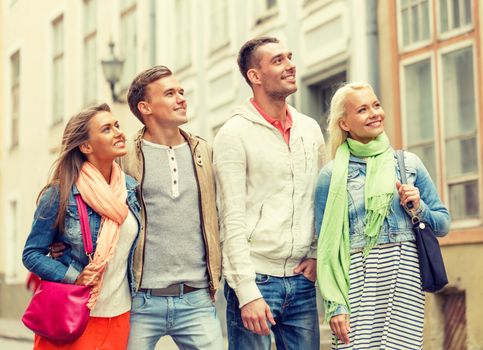 friendship, travel and vacation concept - group of smiling friends walking in the city