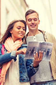 travel, vacation, love and friendship concept - smiling couple with city guide exploring town