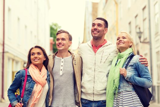 friendship, travel and vacation concept - group of smiling friends walking in the city