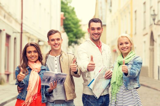 travel, vacation and friendship concept - group of smiling friends with city guide and map showing thumbs up in the city