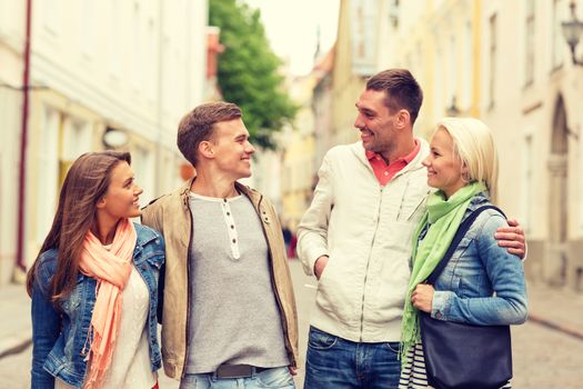 friendship, travel and vacation concept - group of smiling friends walking in the city