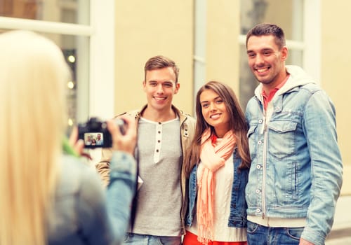 travel, vacation, technology and friendship concept - girl picturing group of friends in city