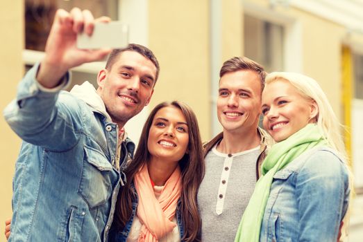 travel, vacation, technology and friendship concept - group of smiling friends making selfie with smartphone camera outdoors