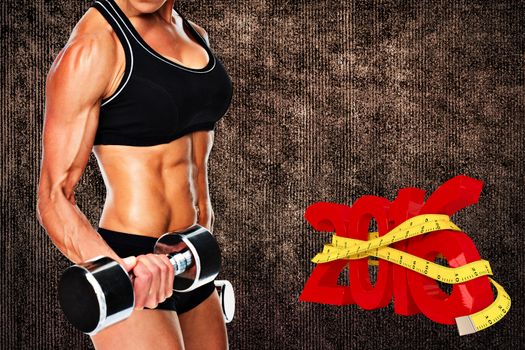 Female bodybuilder working out with large dumbbells mid section against grey background