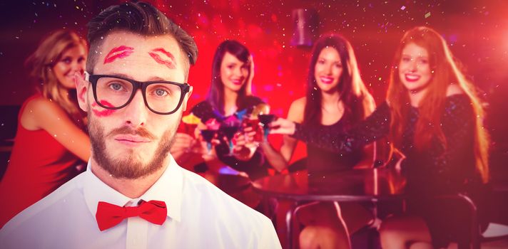 Geeky hipster with kisses on his face against pretty friends drinking cocktails together