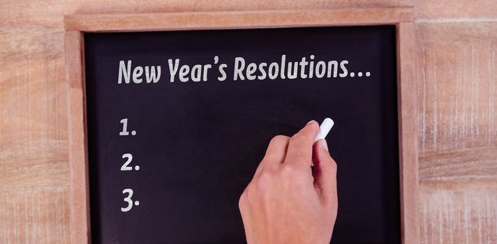 New years resolution list against view of hand writing on blackboard