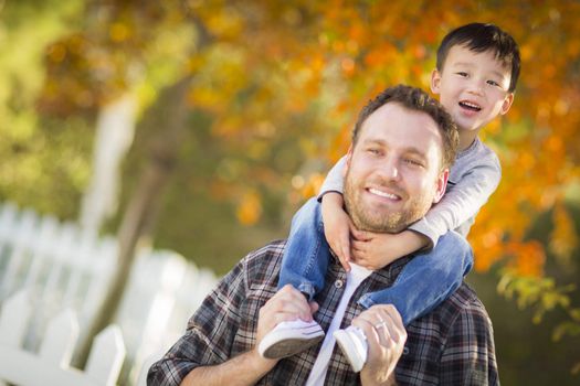 Happy Mixed Race Boy Riding Piggyback on Shoulders of Caucasian Father.