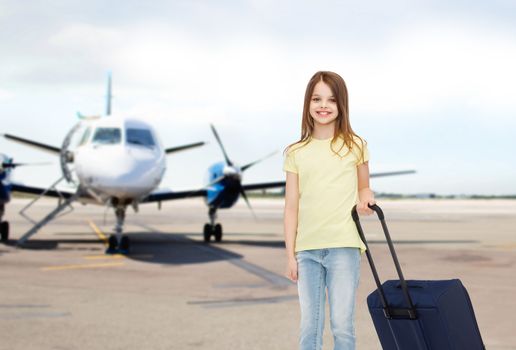 tourism, holiday, vacation, childhood and transportation concept - smiling little girl with travel bag over airport background