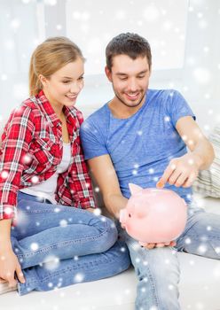 money, home, finance and relationships concept - smiling couple with piggybank sitting on sofa