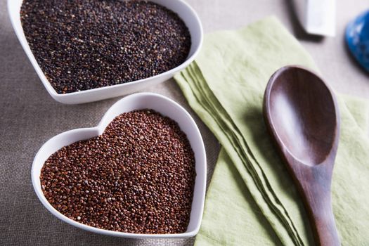 Heart shaped bowls filled with healthy red and black quinoa seeds.