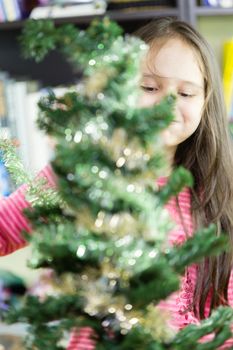 Young girl happily decorating Christmas tree