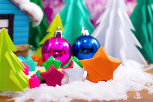 multicolor star folded paper on snow. with christmas ball and tree background