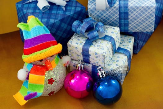 Snowman and gift box with christmas ball on dark yellow background