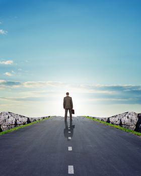 Businessman on road with mountains, rear view