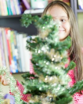 Young girl happily decorating Christmas tree