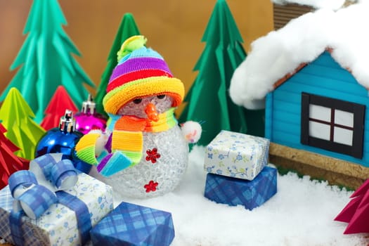 Snowman and gift box with small star paper on the snow field.