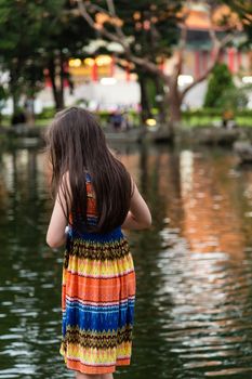 Young girl in colorful dress by lake