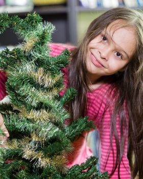 Young girl happily decorating Christmas tree