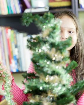 Young girl happily decorating Christmas tree