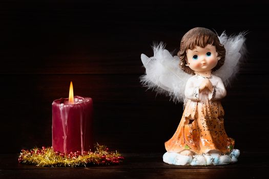 Christmas greeting card with candle and angels on wooden background.