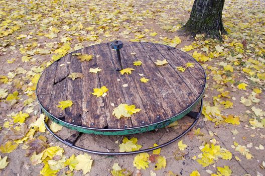 Old used wooden children?s playground toy with yellow fallen leaves