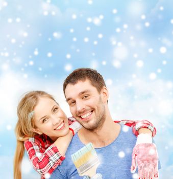 repair, building, love and people concept - smiling couple with paintbrush over blue sky, snow and clouds background