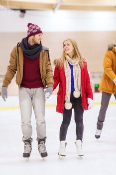 people, friendship, sport and leisure concept - happy couple holding hands on skating rink
